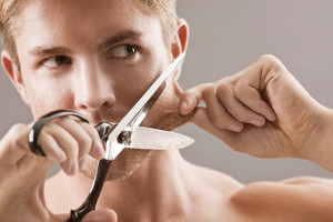 Hombre cortándose la barba con tijeras